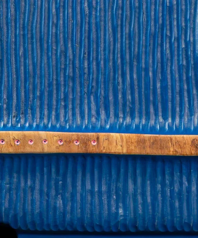 Movimento Azul — faixa de madeira nua atravessando a face azul, com pinos rosa em fila